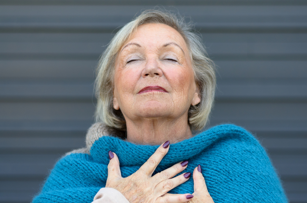 Attractive senior woman savoring the moment standing with her eyes closed and head tilted back with a serene expression