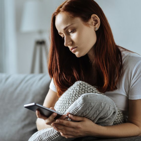 Sad young woman holding her smartphone