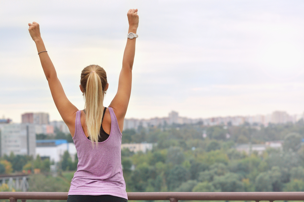 Young sporty woman stretching arms, preparing for working out, outdoor training, warming up after or before fitness on fresh air