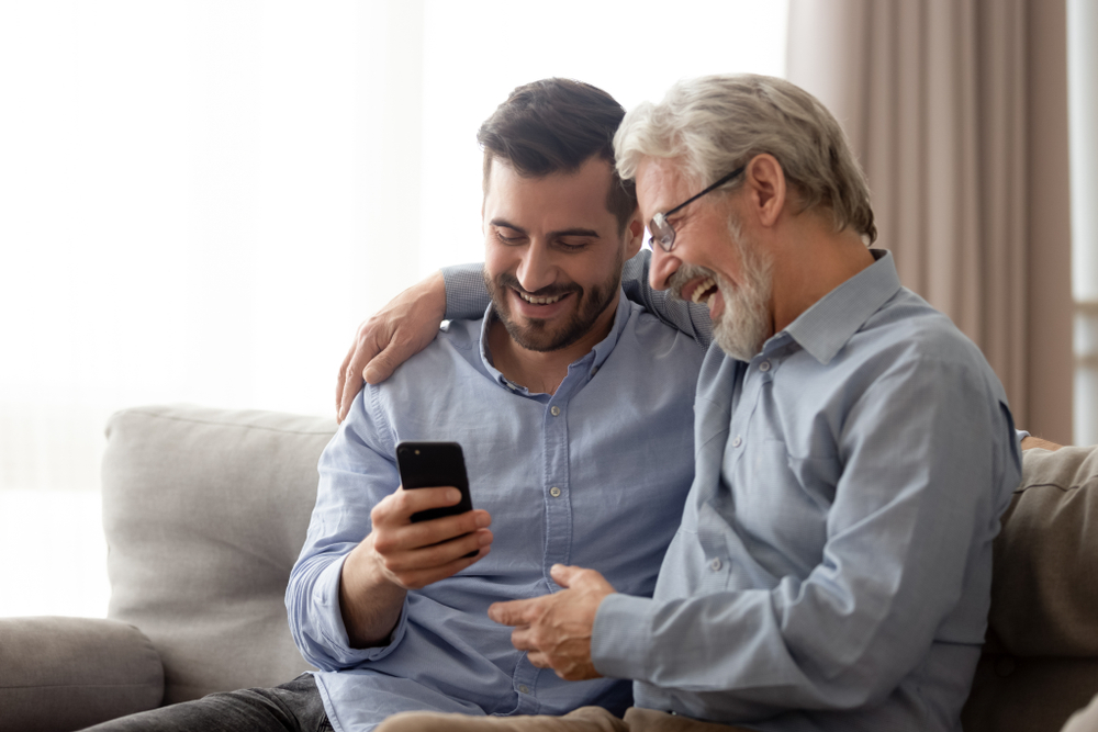 happy millennial man rest on sofa speak with elderly father enjoy leisure family weekend at home