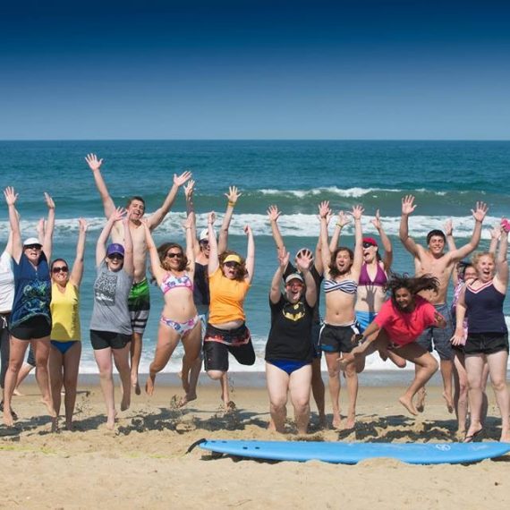 Young adult cancer fighters and survivors jumping on a beach