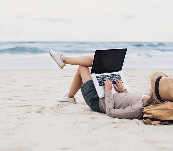 Young woman using laptop computer on a beach.