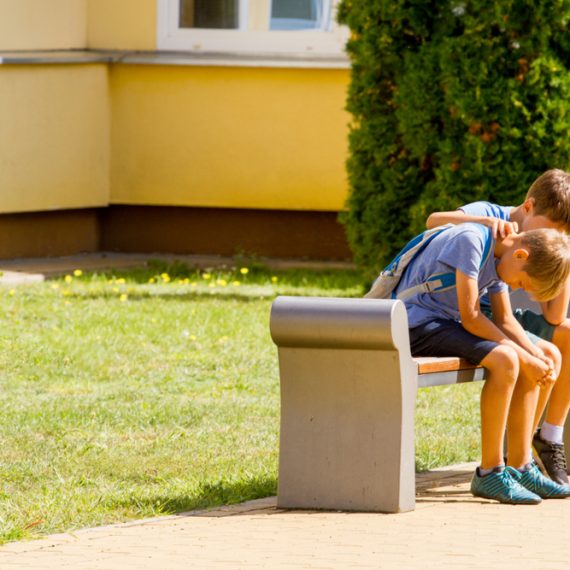 Kid comforting consoling upset sad boy in school yard
