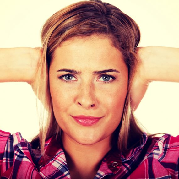 Young woman covering her ears.