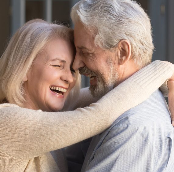 Happy mature couple in love embracing, laughing grey haired husband and wife with closed eyes, horizontal banner, middle aged smiling family enjoying tender moment, happy marriage, sincere feelings