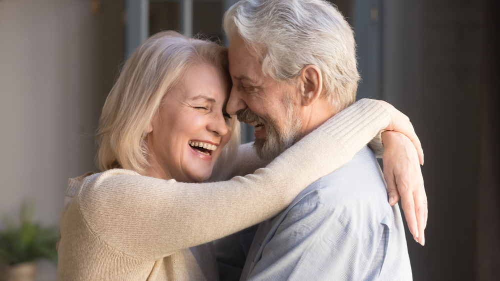 Happy mature couple in love embracing, laughing grey haired husband and wife with closed eyes, horizontal banner, middle aged smiling family enjoying tender moment, happy marriage, sincere feelings