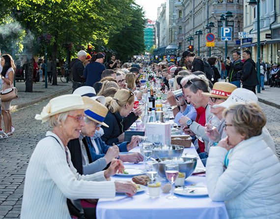 Long table with  people eating and drinking together in Finland