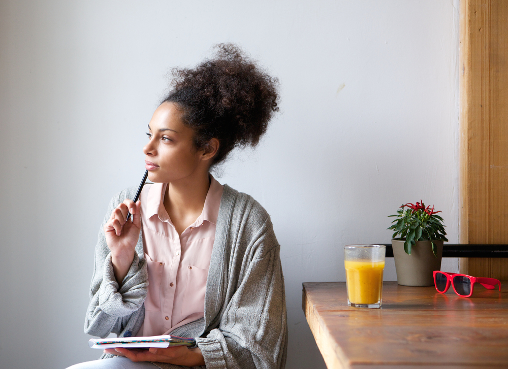 Portrait of a young woman sitting at home with pen and paper