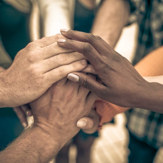 Young people putting their hands together. Friends with stack of hands showing unity and teamwork