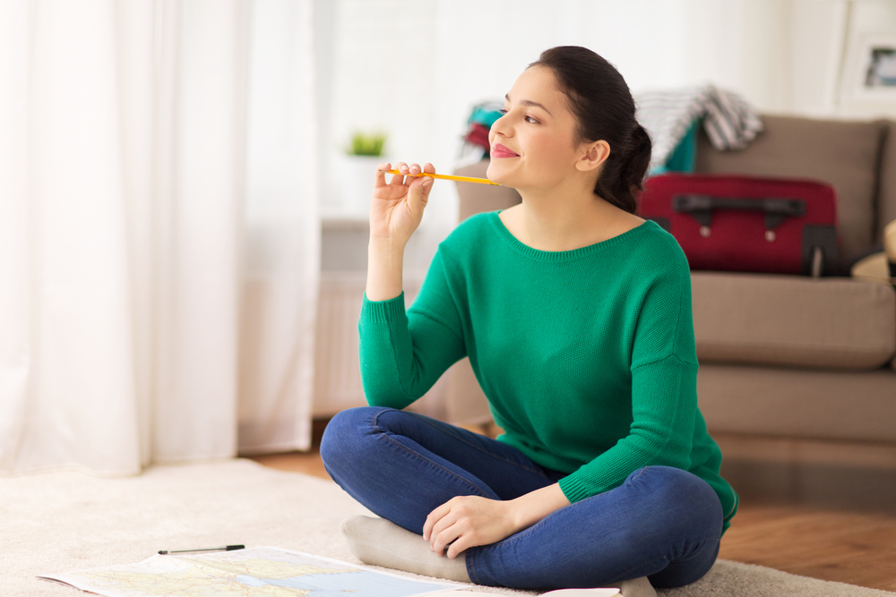 happy young woman with map at home going on trip