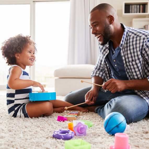 Young father playing with daughter in the sitting room