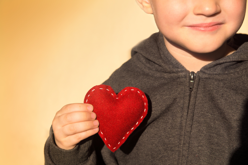 Red heart in child hands. Kindness concept, gift, hand made valentine, close up.