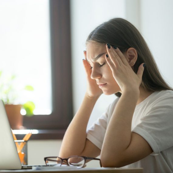 Stress and headache behind laptop on job. Overwork, distress, negative emotions concept