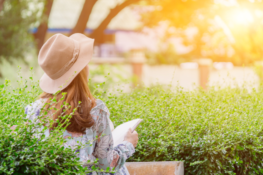 girl holds the bible in her hand and is praying for the Holy Scriptures in the park alone in the bright summer morning.