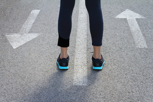 Choice concept. Woman standing between arrows showing different directions. Go forward or go back, Move Ahead